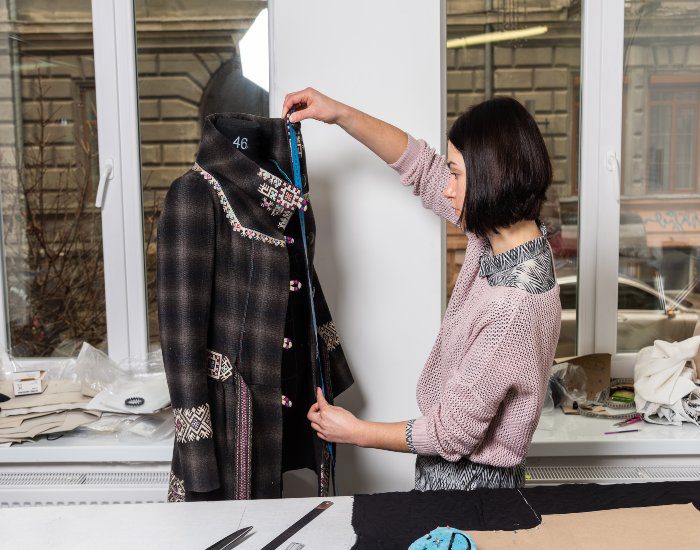 A tailor at Richard Bennett Custom Tailors is measuring a stylish women's overcoat in Chicago, IL